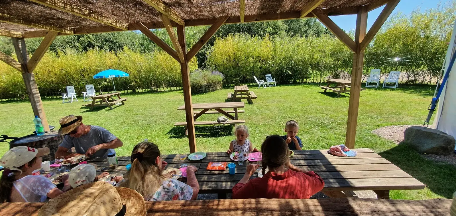 Jardin avec tables de pique-nique et parasols au Domaine de l'Entre-Deux