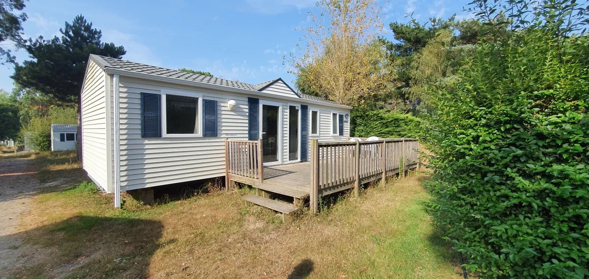 Vue extérieure du logement familial avec terrasse en bois dans un cadre verdoyant en Bretagne